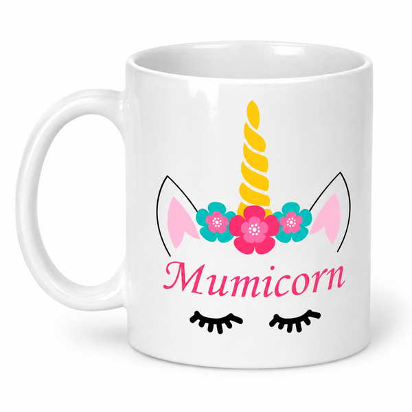 A white ceramic mug featuring a colorful 'Mumicorn' design with a yellow horn, pink and blue flowers, black eyelashes, and pink ears on a white background.
