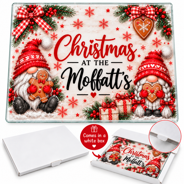 A square Christmas-themed glass plate or decorative board printed with the phrase 'Christmas at the Moffatt's,' featuring two gnome characters, red bows, pine branches, snowflakes, and gingerbread cookies. The image also shows a white box and a circular inset demonstrating the lid closure, with a red badge noting it comes in a white box.