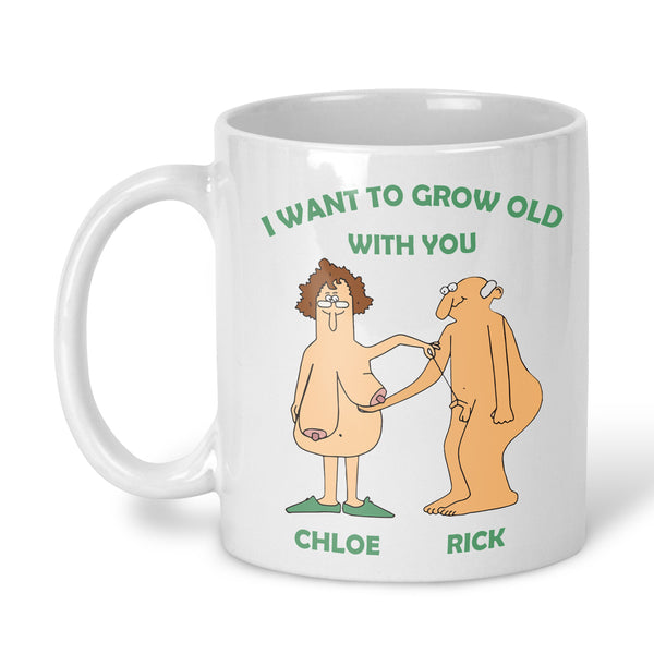 A white ceramic mug with a printed cartoon graphic and text. The design features a nude woman and an orange humanoid man with green text above reading 'I WANT TO GROW OLD WITH YOU'. Personalised with any names
