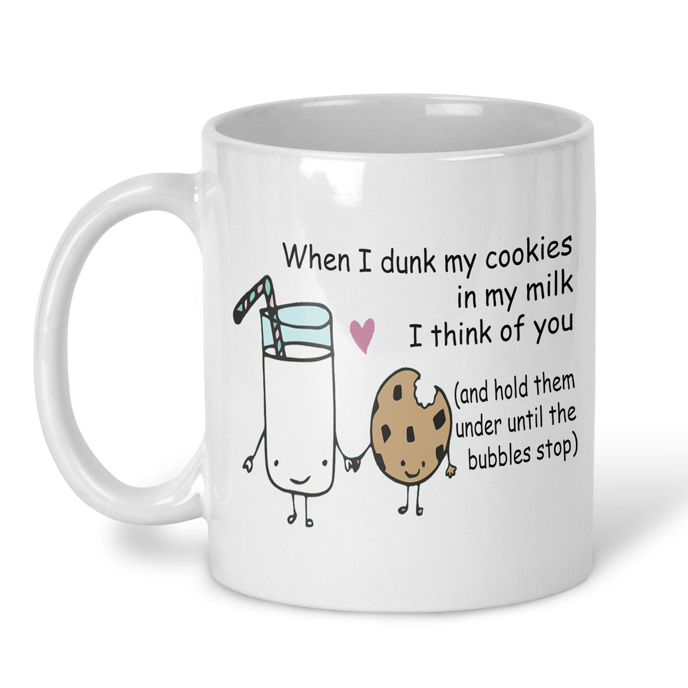 A white ceramic mug with a cute cartoon graphic of a milk glass and a cookie holding hands, accompanied by the text 'When I dunk my cookies in my milk I think of you (and hold them under until the bubbles stop)'.