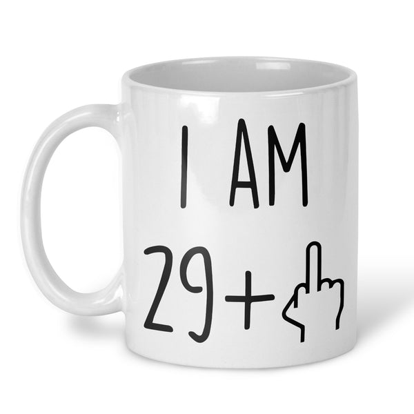 A white ceramic coffee mug with black printed text reading 'I AM 29+' and a hand gesture icon, shown on a clean white background.